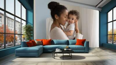 Happy young African American mom hold in hands hug cute little ethnic baby toddler show love care. Smiling biracial mother embrace cuddle small newborn infant child. Motherhood, childcare concept. Wall mural