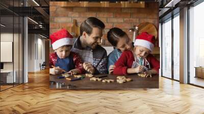 Happy young Caucasian parents with two small kids have fun decorate Christmas biscuits in kitchen together. Smiling family with little children baking cookies for New Year winter holidays celebration. Wall mural