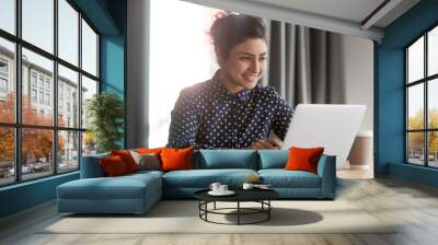 Happy young indian businesswoman using computer sit at office desk Wall mural