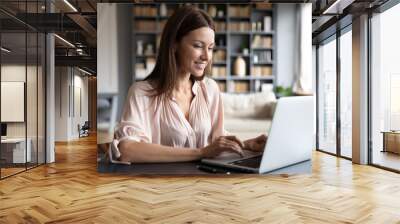 Happy young woman browsing internet on laptop Wall mural