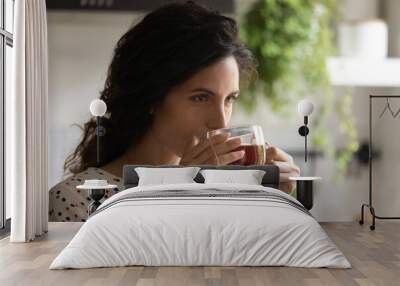 Head shot close up of beautiful woman drinking black tea, enjoying morning, breakfast, starting new day, young female holding glass cup with tea bag inside, hot beverage, relaxing during break Wall mural