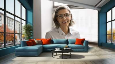 Head shot close up profile picture of beautiful middle-aged businesslady posing in workplace, smiling, look at camera, feel satisfied with career growth and success. Business portrait, professionalism Wall mural