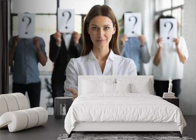 Head shot portrait confident businesswoman hr manager with candidates standing behind, workers hiding faces behind papers with question marks, identity and equality at work, recruitment process Wall mural