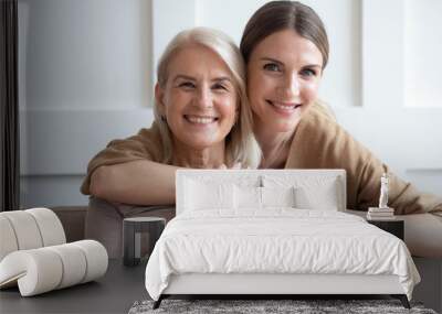 Head shot portrait happy loving adult daughter hugging older mother, smiling young woman and mature mum or grandmother looking at camera, holding hands, family photo, two generations bonding Wall mural