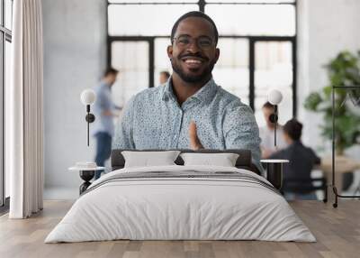 Head shot portrait smiling African American businessman wearing glasses showing thumb up, looking at camera, standing in modern office, recommending corporate service, good career, satisfied client Wall mural