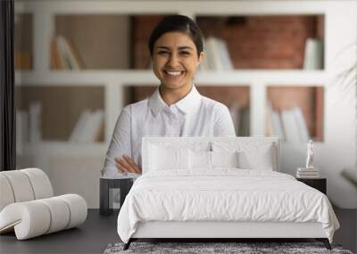 Head shot portrait smiling Indian businesswoman with arms crossed looking at camera, standing in modern office, happy successful confident woman entrepreneur executive posing for corporate photo Wall mural