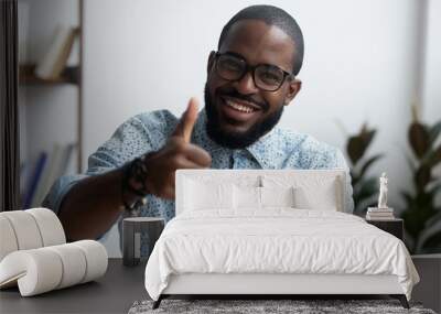 Head shot positive confident black businessman sitting at office desk smiling looking at camera showing hand gesture thumbs up sign symbol of good result, recommendation and success in work or study Wall mural