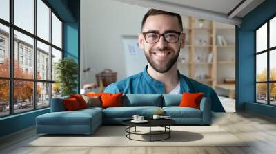 Headshot portrait of smiling Caucasian young man CEO or boss in glasses posing in modern office, happy motivated European male employee in spectacles show confidence and leadership at work Wall mural