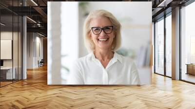 Headshot portrait of smiling senior Caucasian businesswoman in glasses pose in office on working day. Close up profile picture of happy middle-aged female employee or CEO show success at workplace. Wall mural