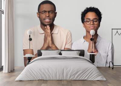 Hopeful ethnic man and woman hold hands in prayer Wall mural