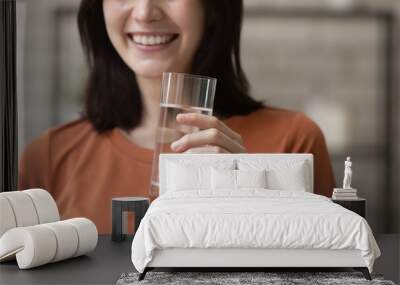 I recommend. Close up of young woman holding glass of pure fresh natural water in hand advertising demonstrating it to spectator. Cropped portrait of smiling lady promoting healthy lifestyle nutrition Wall mural