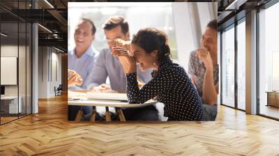 indian woman laughing at funny joke eating pizza with diverse coworkers in office, friendly work tea Wall mural