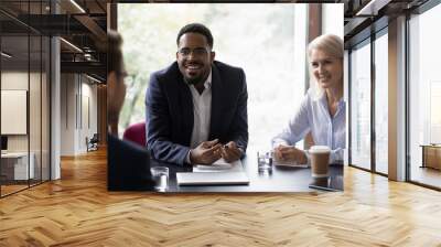 Inspired african businessman talking about benefits of his startup on meeting with potential investors, excited black agent and his mature female colleague convincing client in profit of their product Wall mural