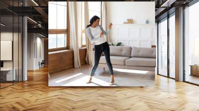 Joyful black young woman dancing in bright modern living room. Happy girl have fun at home on lazy weekend, receive good or pleasant news, celebrate moving to new apartment or house Wall mural