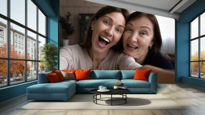 Kidding with mommy. Joyful grown daughter joking laughing taking funny selfie together with retired mother. Young and elderly women two sisters mom and adult child have fun at home shoot self portrait Wall mural