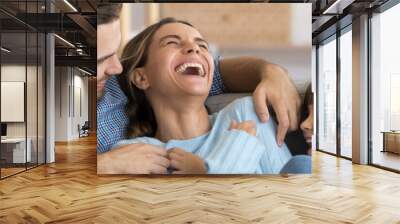 Laughing husband and daughter tickling mother family play together having fun resting on sofa at home close up photo. Weekend activities, affection concept. Horizontal banner for website header design Wall mural