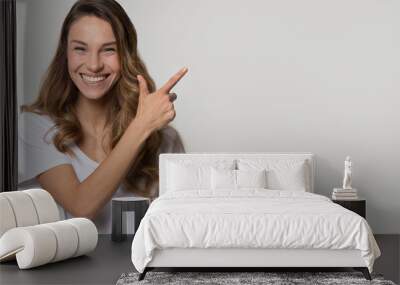 Laughing woman pose over white grey background pointing at copyspace Wall mural