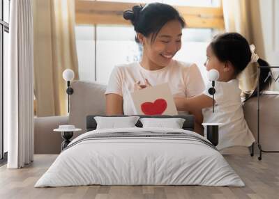 Little Asian girl greeting mom presenting postcard Wall mural