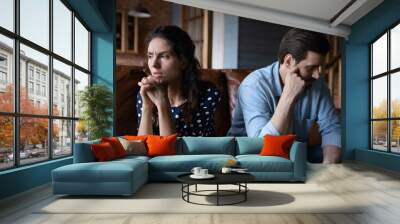 Marital split. Depressed young husband wife sit on sofa turn backs to each other feel upset empty think of separation divorce. Stubborn selfish spouses demonstrate indifference after family dispute Wall mural