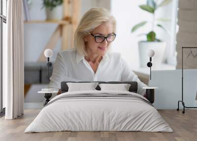 Middle-aged businesswoman typing on pc holds paper prepares report Wall mural