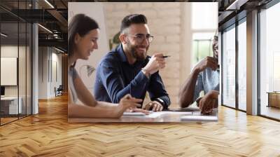 Middle eastern ethnicity employee and colleagues talking sitting at desk Wall mural