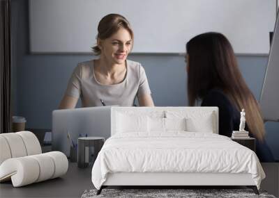 Millennial businesswomen working at laptop negotiating about future partnership, female partners talking during boardroom meeting, colleagues discussing company projects, sharing ideas in office Wall mural