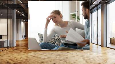 Millennial couple have fight over documents at home, man and woman sit on couch upset about bad news in letter, frustrated wife cry reading negative notice from bank, spouses dispute over bills Wall mural