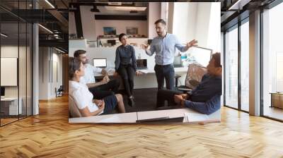 Millennial male leader working with diverse team at office. Wall mural