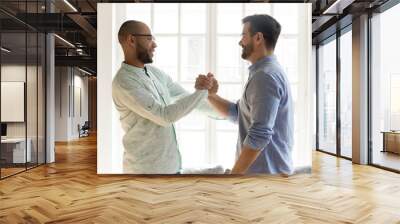 Mixed race male friends in eyewear shaking hands. Wall mural