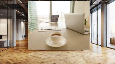 Modern office workplace with conference negotiating table and two laptops, focus on cup of coffee, break during work, preparation to formal meeting in boardroom, executive management working space Wall mural