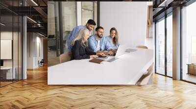 Multiethnic business team of positive different aged colleagues watching Internet content on laptop together. Project manager showing online work project presentation on computer to happy coworkers Wall mural