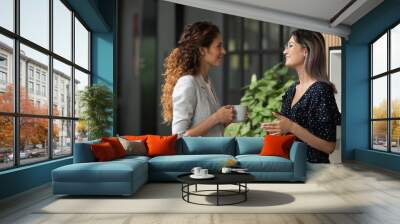 Multiethnic female colleagues chat during coffee break Wall mural