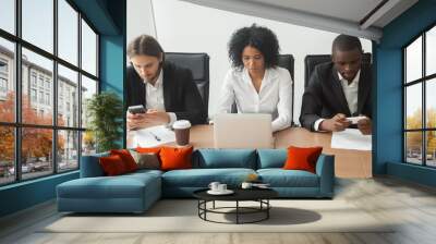 Multiracial business team people sitting at office table using corporate devices, african businesswoman working online on laptop while her male colleagues using mobile phone apps at group meeting Wall mural