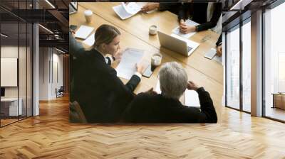 Negotiations concept, different businesspeople discussing deal details at group meeting, young and senior partners team thinking talking consulting about contract sitting at conference office table Wall mural