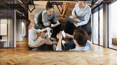 Office colleagues using digital devices during meeting, consulting internet for new ideas and brainstorming. Millennial employees browsing social media during work break. Online communication concept Wall mural