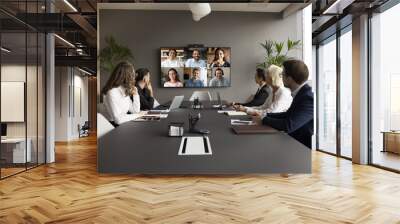 Office staff meeting with diverse freelance team on online video conference, making group call on internet, sitting at table looking at electronic board with head shots, discussing work project Wall mural