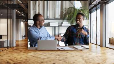 Overjoyed African American male business partners shake hands close deal after success office negotiation. Smiling biracial businessmen handshake get acquainted greet at meeting. Partnership concept. Wall mural