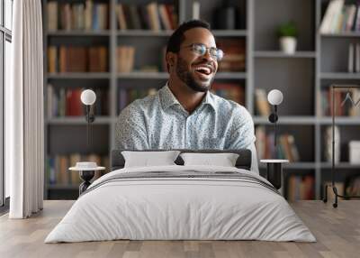 Overjoyed biracial young man in glasses stand laugh talking with friend or colleague, happy excited African American millennial male have fun engaged in pleasant conversation at home or workplace Wall mural