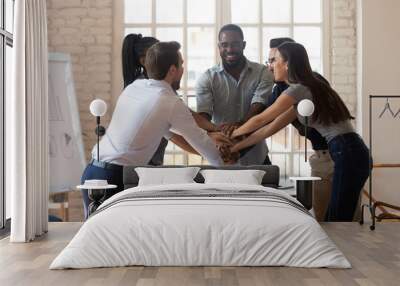 Overjoyed happy multiethnic young teammates celebrating employees unity at office. Wall mural