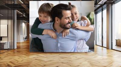 Overjoyed loving young Caucasian father have fun engaged in funny game activity with two small children at home. Happy dad parent and little kids play together, relax on family weekend indoors. Wall mural