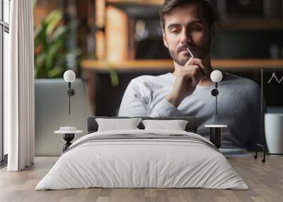 Pensive male thinking over problem solution working on laptop Wall mural