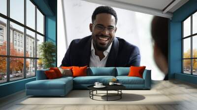 Pleasant business conversation. Positive afro american executive consulting customer, happy dark-skinned employee talking to colleague at workplace, smiling reporter interviewing a person, close up Wall mural