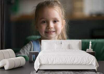 Portrait of cute little girl indoors, happy funny pretty child with sincere smiling face looking at camera, adorable positive cheerful kid posing at home on sofa, beautiful preschool model headshot Wall mural