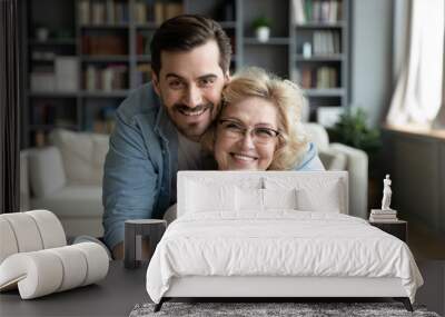 Portrait of grateful adult son hugging senior mother Wall mural