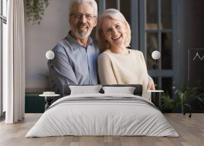 Portrait of happy elderly spouses posing for picture at home Wall mural