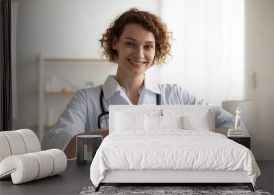 Portrait of happy young Caucasian female doctor in white medical uniform show heart love hand gesture or sign. Smiling woman nurse share care and support to patients. Good hospital service concept. Wall mural