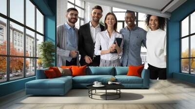 Portrait of smiling diverse multiracial team of professionals pose in modern office show unity leadership. Happy multiethnic young employees colleagues have meeting at workplace. Teamwork concept. Wall mural