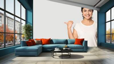 Portrait of smiling Indian woman isolated on grey studio background point at blank empty copy space. Happy millennial mixed race female show good promotion deal or sale discount. Commerce concept. Wall mural