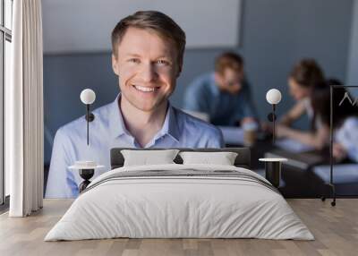 Portrait of smiling middle-aged male employee posing during company team meeting in boardroom, confident happy businessman looking in camera, making picture for corporate catalogue during briefing Wall mural