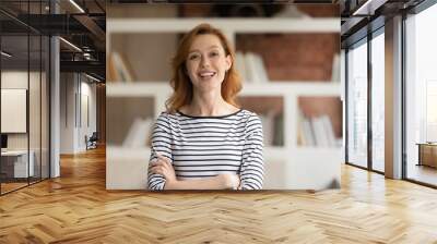 Portrait of smiling young Caucasian businesswoman pose in modern office. Happy 30s red-haired European female employee or worker show leadership and success at workplace. Recruitment concept. Wall mural